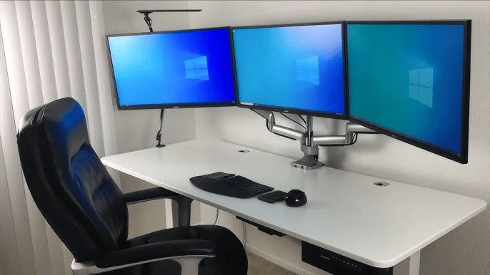 Desk with three computer monitors {{brizy_dc_image_alt imageSrc=